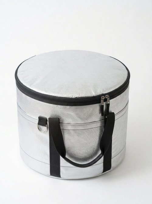 Aluminized Kevlar silver cylindrical insulated bag with black zipper trim, dual black handles, and a top zipper closure, photographed on a clean white background.